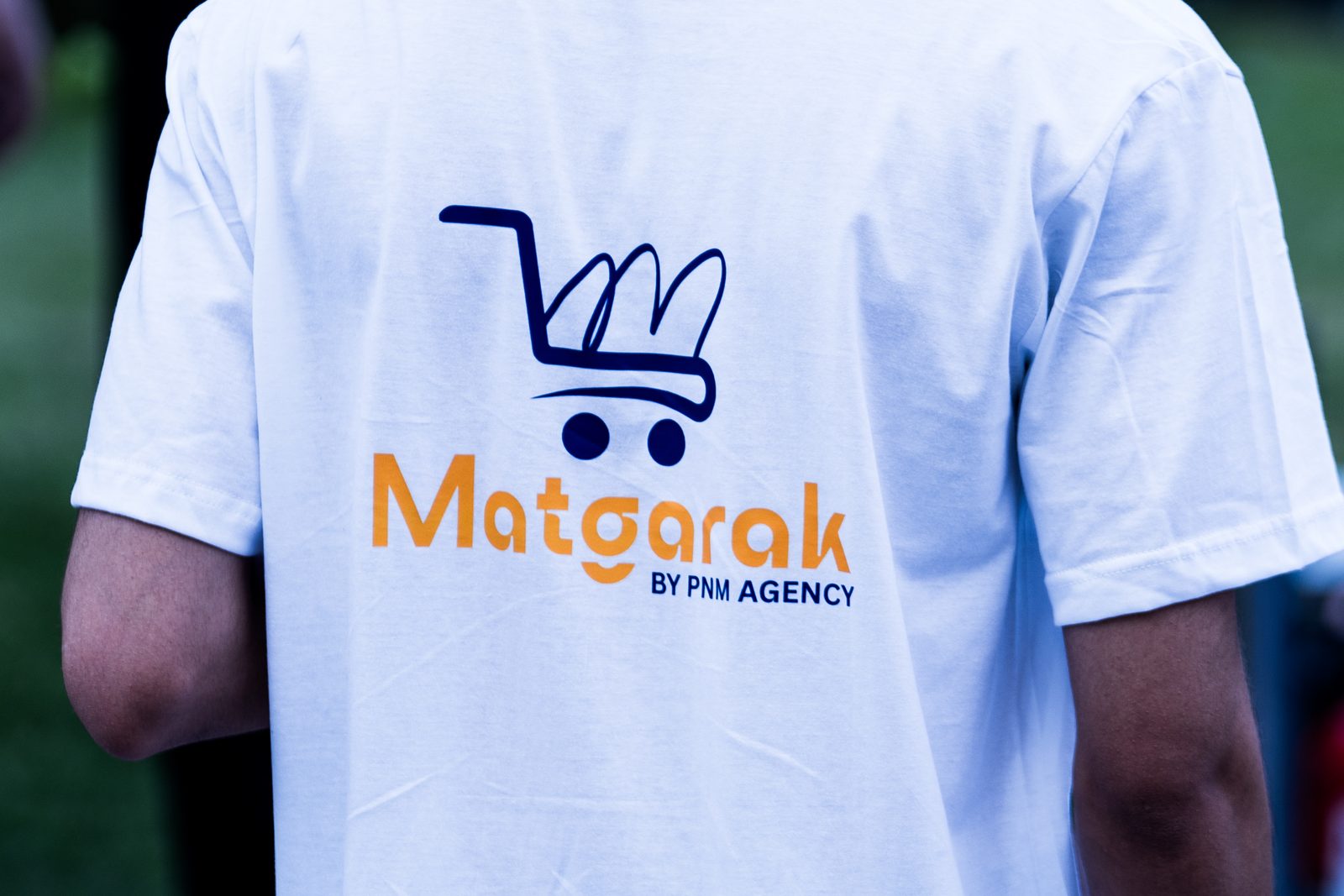 The back of a white t-shirt printed with the Matgarak logo and "by PNM Agency"